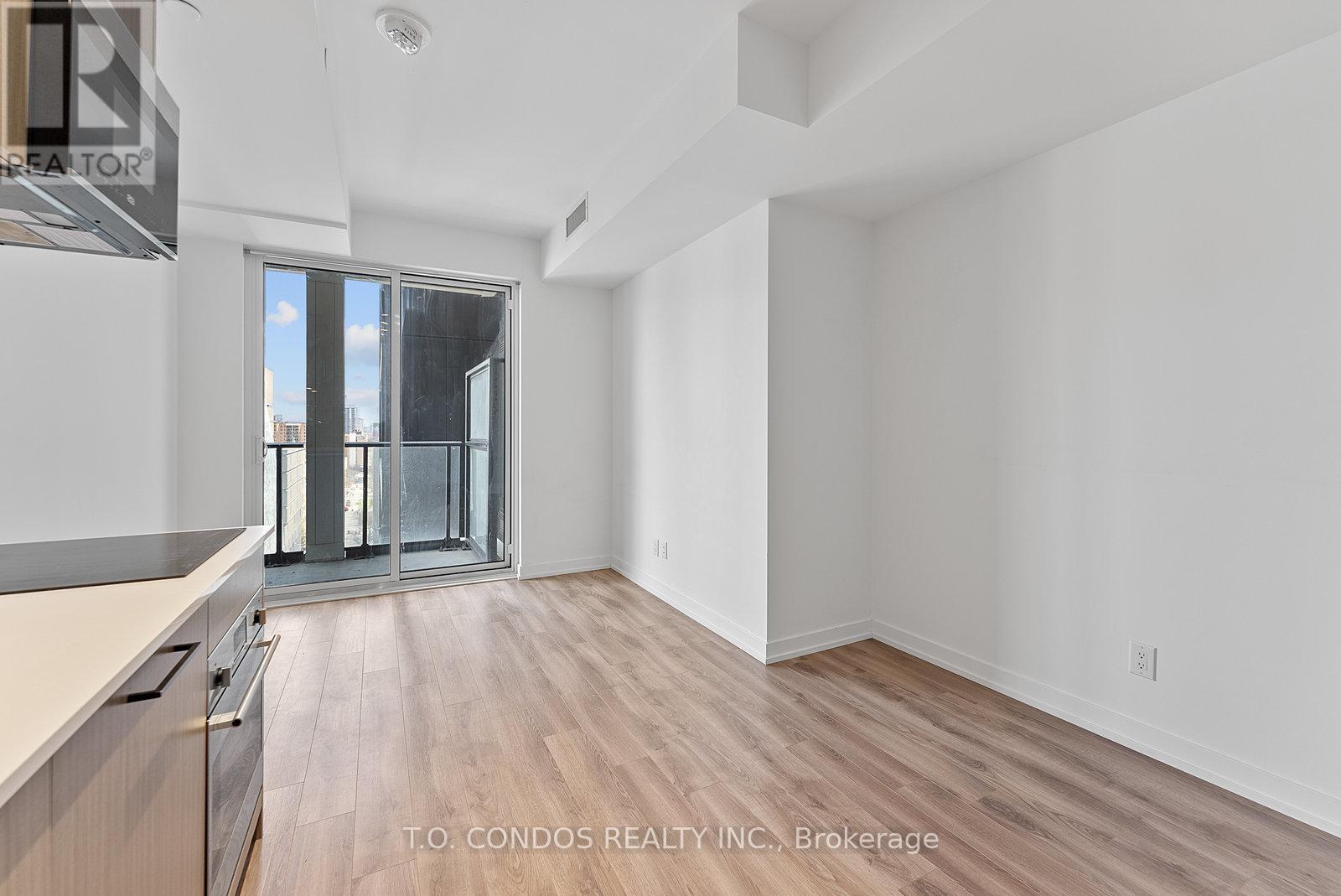 A spacious, empty room with wooden flooring and white walls.