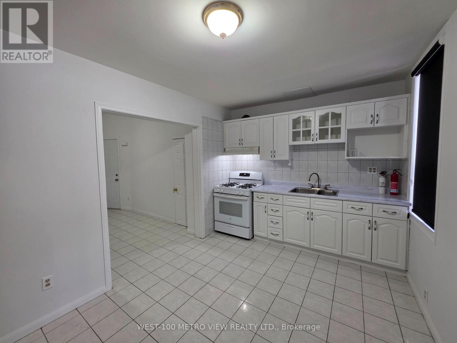 A white kitchen with tile flooring and white cabinets.
