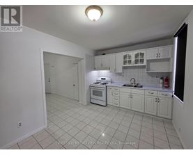 A white kitchen with tile flooring and white cabinets.