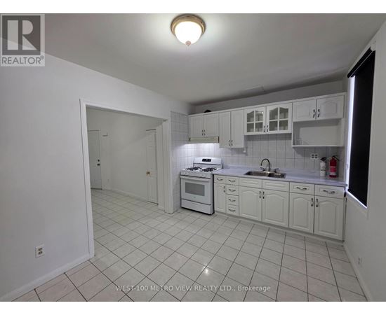 A white kitchen with tile flooring and white cabinets.