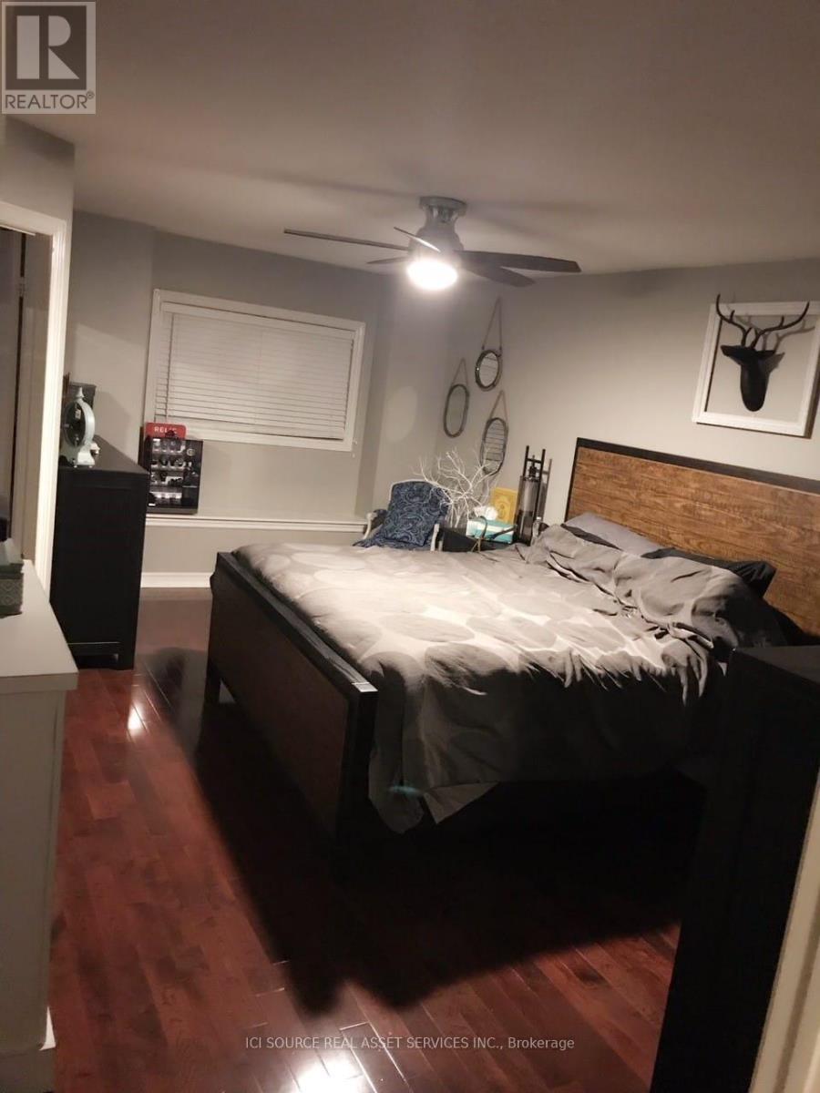 A bedroom with a bed, a ceiling fan, and a deer head on the wall.