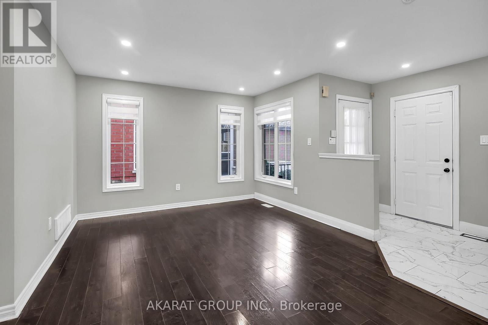 A spacious room with wooden flooring and white walls.