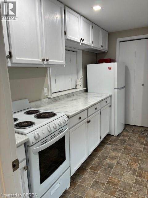 A kitchen with white cabinets and a white stove top oven.