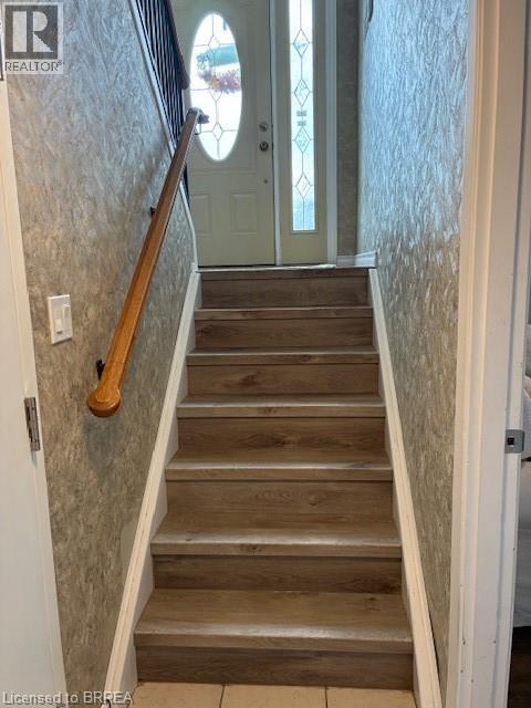 A staircase with a wooden handrail and tiled walls.