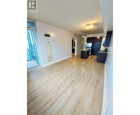 A spacious room with wooden flooring and a large window.