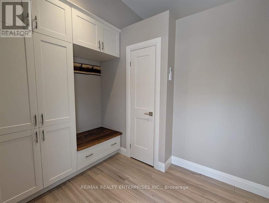 A white cabinet with a door open is in a room with light wood flooring.