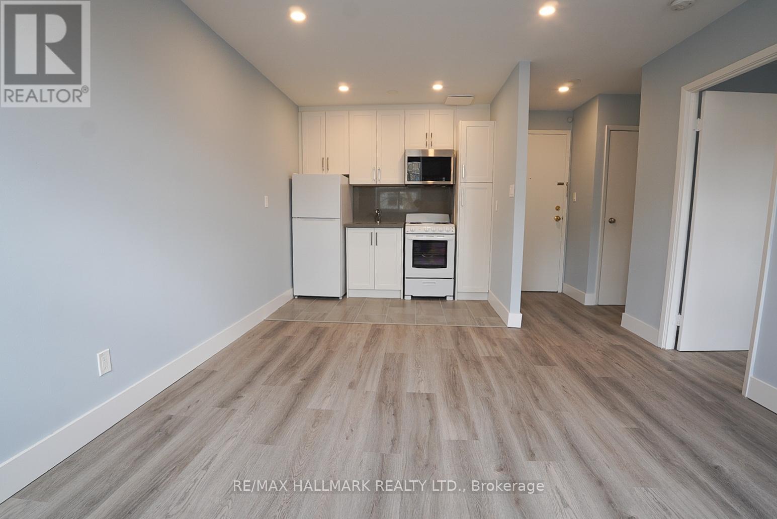 A spacious room with a kitchenette and wooden flooring.