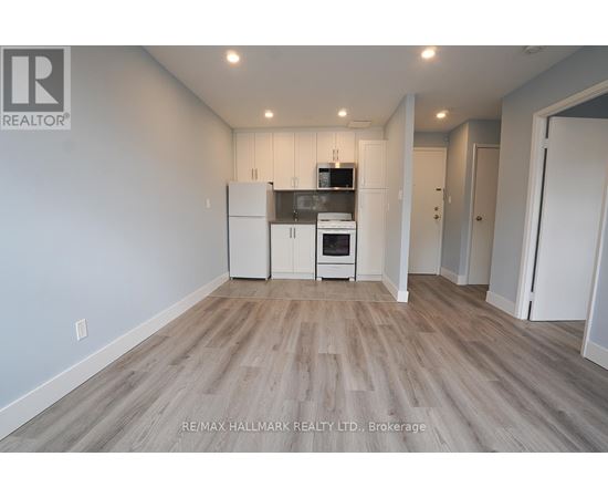 A spacious room with a kitchenette and wooden flooring.