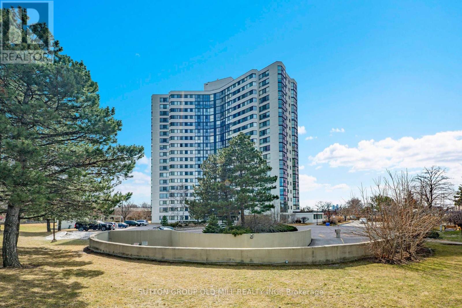 A tall building with a lot of windows is surrounded by trees and grass.