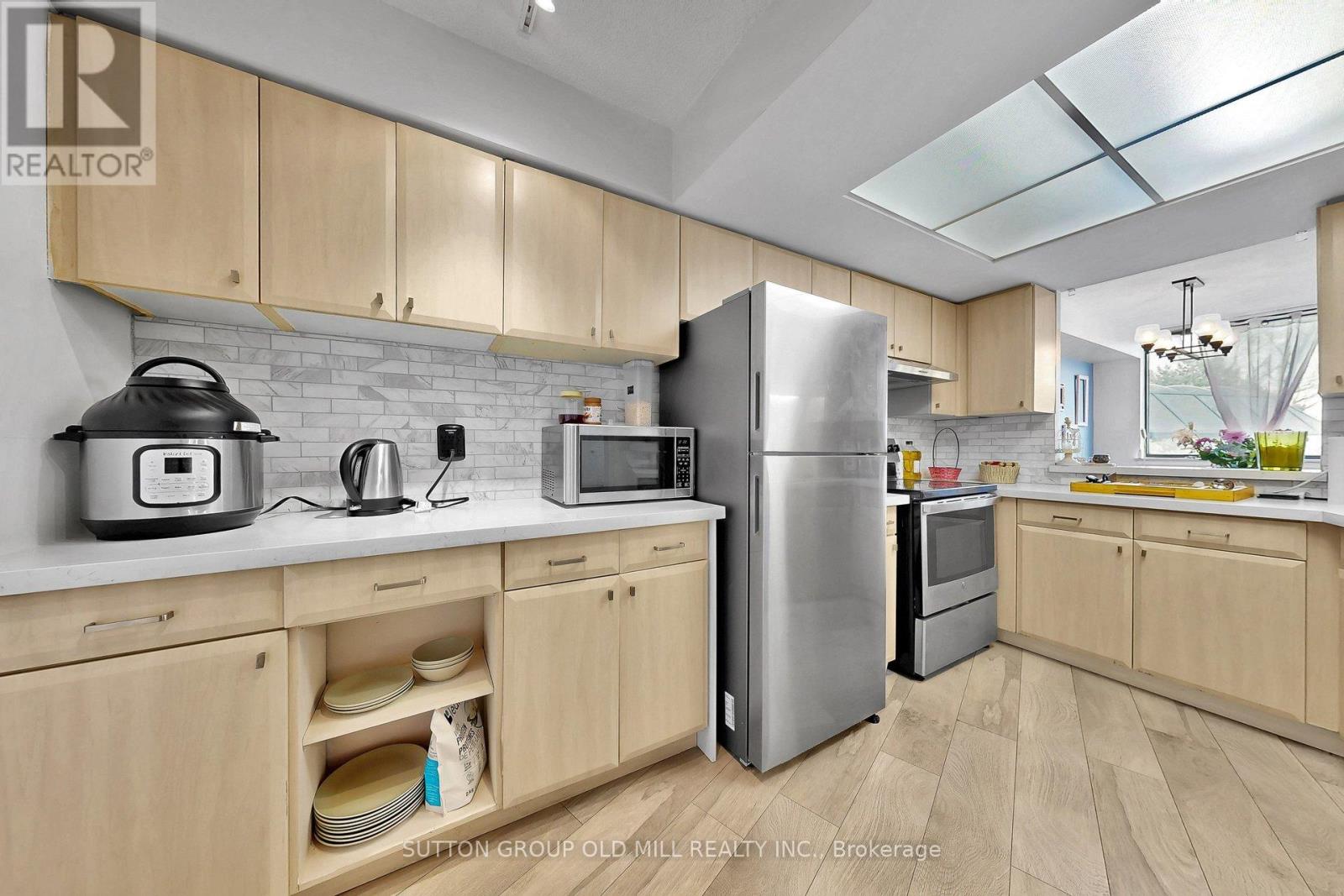 A kitchen with wooden cabinets and a stainless steel refrigerator.