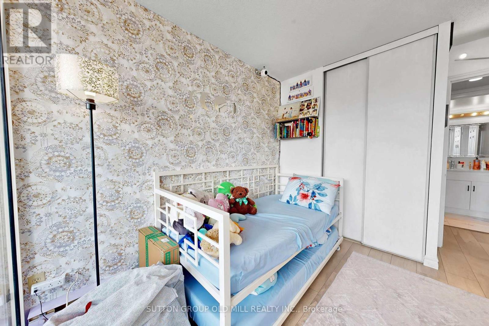 A small child's bedroom with a white bed and a floral wallpaper.