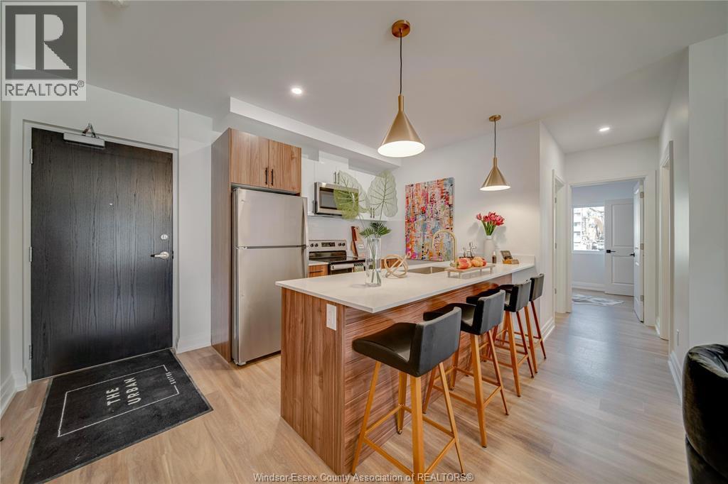 A modern kitchen with wooden cabinets and a black mat on the floor.
