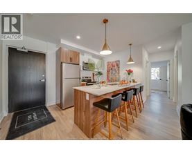 A modern kitchen with wooden cabinets and a black mat on the floor.