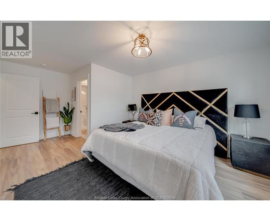 A bedroom with a large bed and a lamp on the side table.
