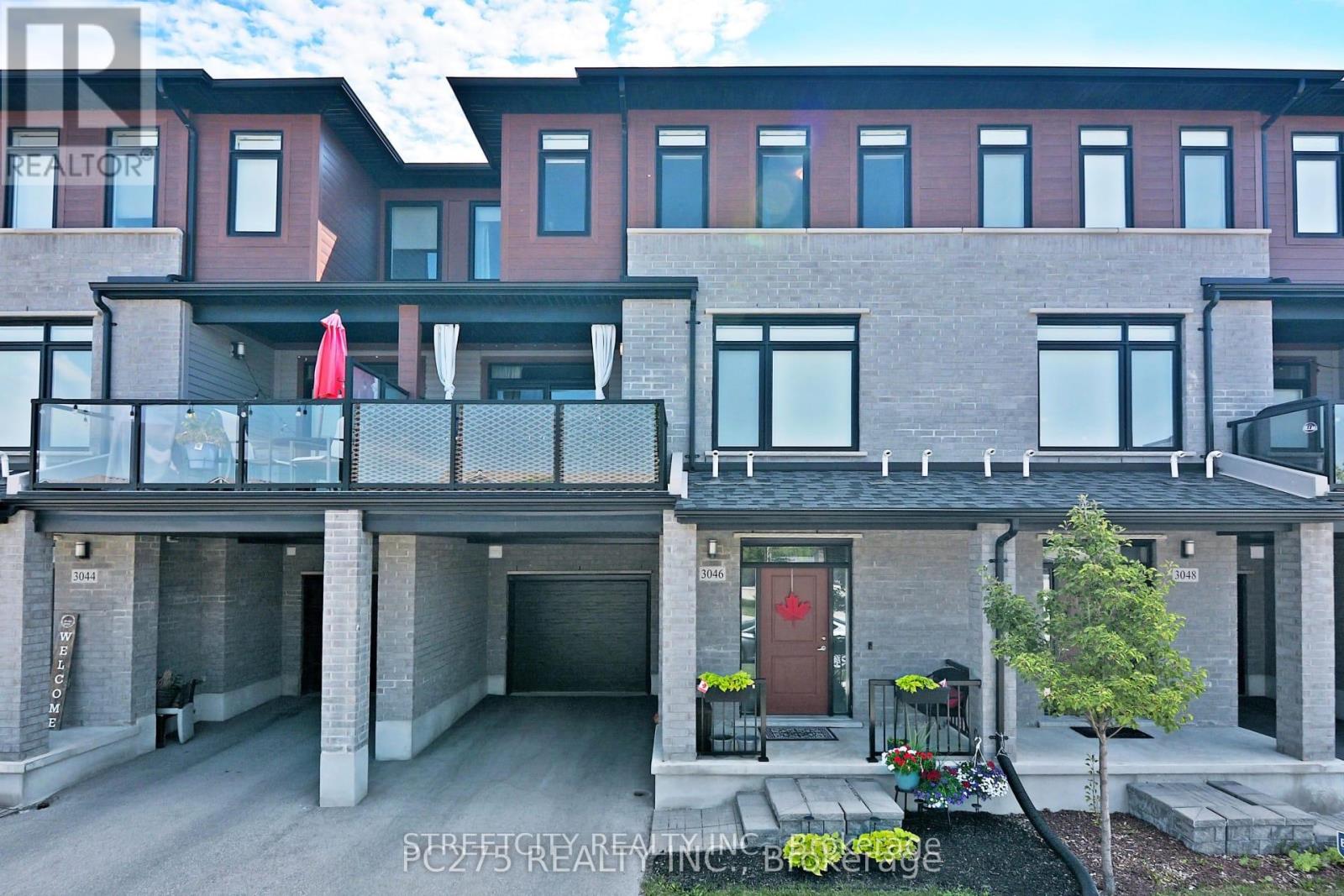 A modern two-story apartment building with a balcony and a red door.
