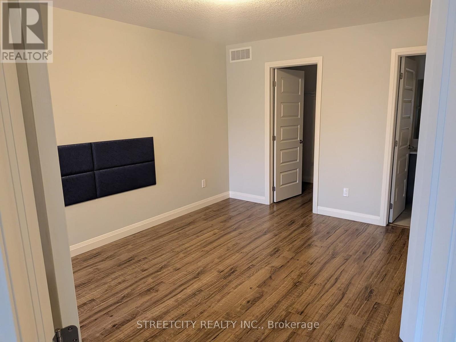 A room with wooden flooring and a wall-mounted TV.