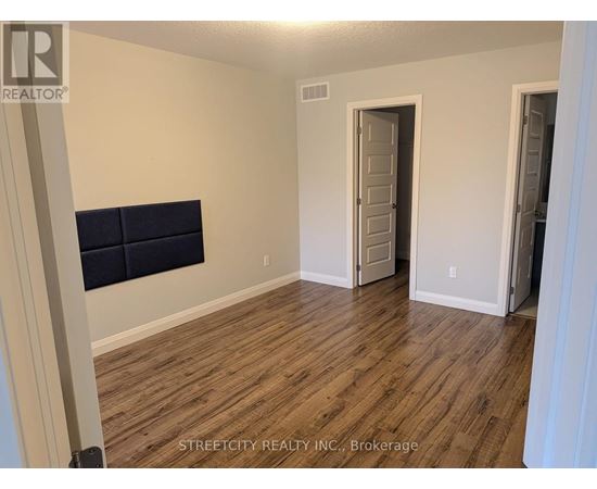 A room with wooden flooring and a wall-mounted TV.