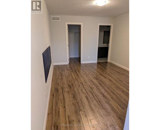 A room with wooden flooring and a flat screen TV mounted on the wall.