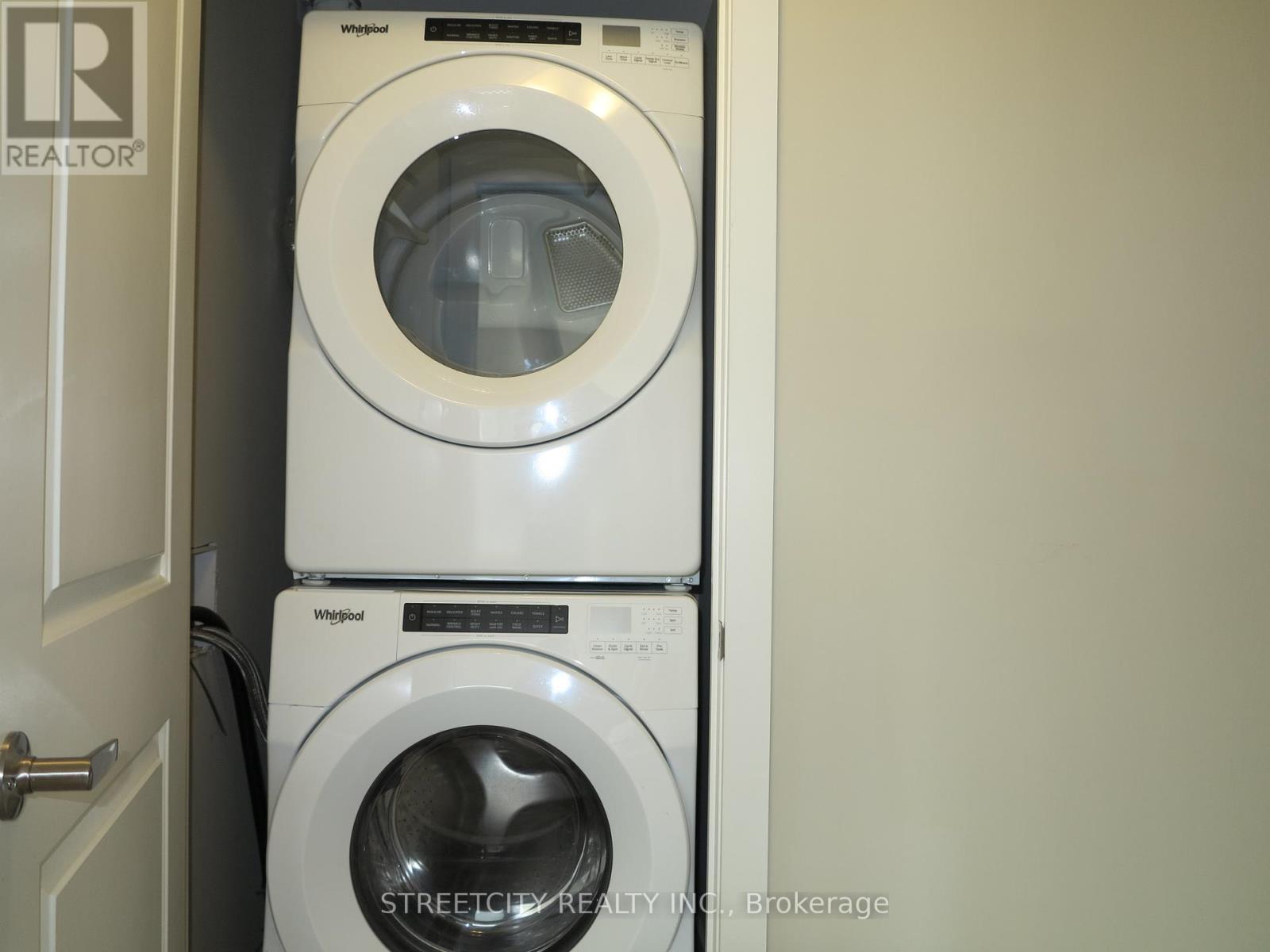 Two white Whirlpool washing machines stacked on top of each other in a small room.