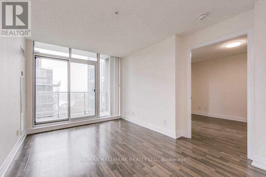 A spacious room with a large window and wooden flooring.