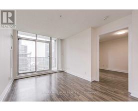 A spacious room with a large window and wooden flooring.