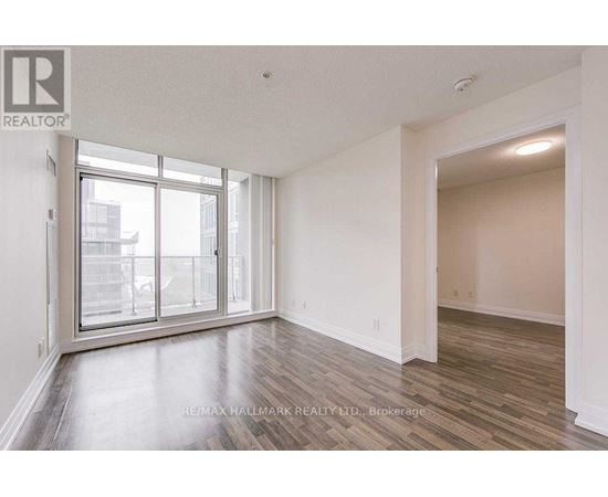 A spacious room with a large window and wooden flooring.