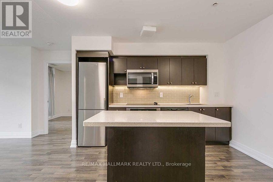 A modern kitchen with a center island and a refrigerator with a glass door.