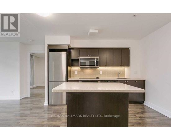 A modern kitchen with a center island and a refrigerator with a glass door.