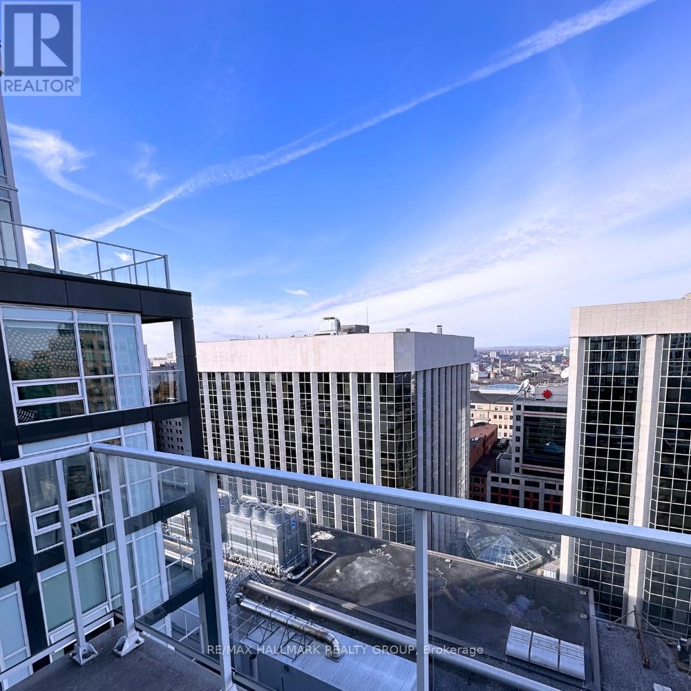 A balcony overlooks a cityscape with buildings and a clear sky.