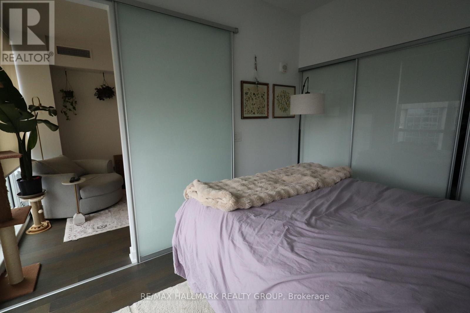 A bedroom with a purple bedspread and a mirror on the wall.