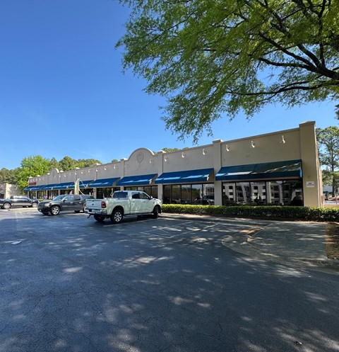 A white truck is parked in front of a building with blue awnings.