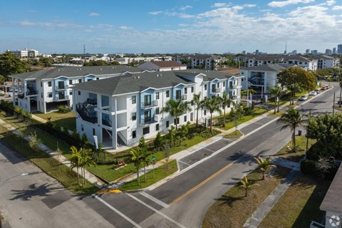 A street view of a residential area with apartment buildings and palm trees.