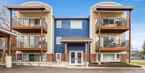 A blue and beige apartment building with a white door and windows.