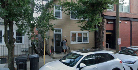 A white car is parked in front of a house.