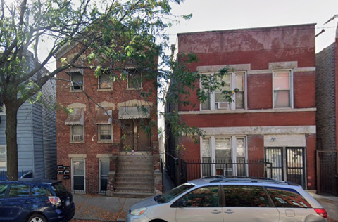 A red brick building with a black gate in front.