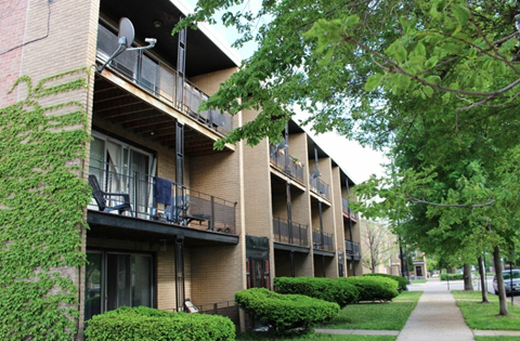 Apartment building with balconies and greenery in front.