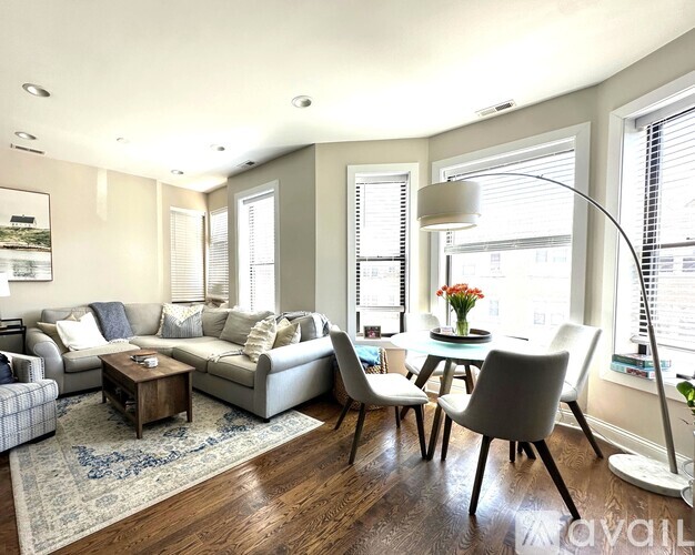 A living room with a grey couch, a coffee table, and a dining table with chairs.