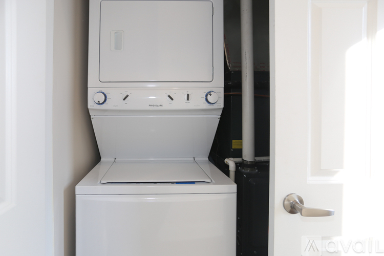 A white washing machine is in a small space next to a door.