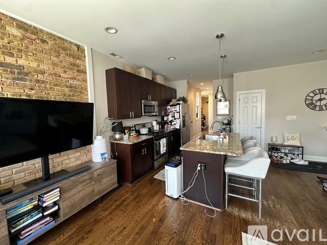 A kitchen with a brick wall and wooden floors.