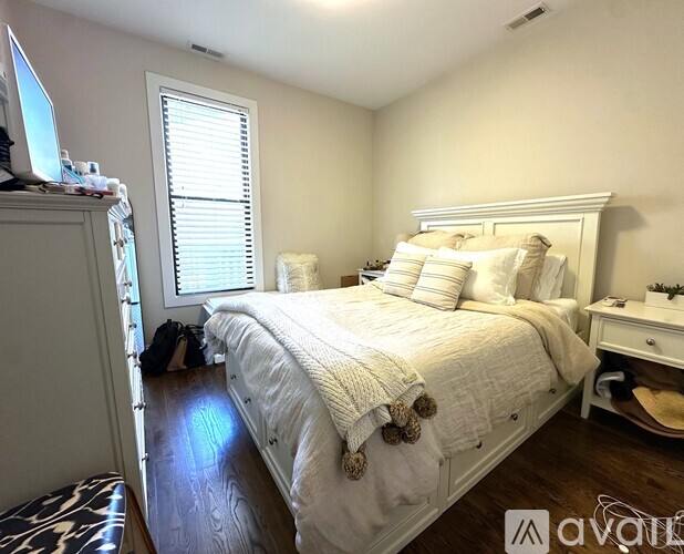 A bedroom with a large bed and a window with blinds.