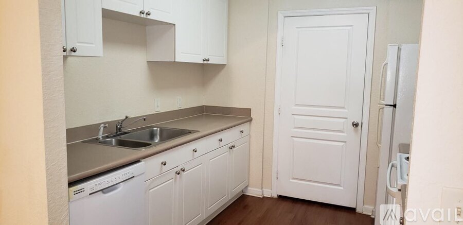 A kitchen with white cabinets and a white door.