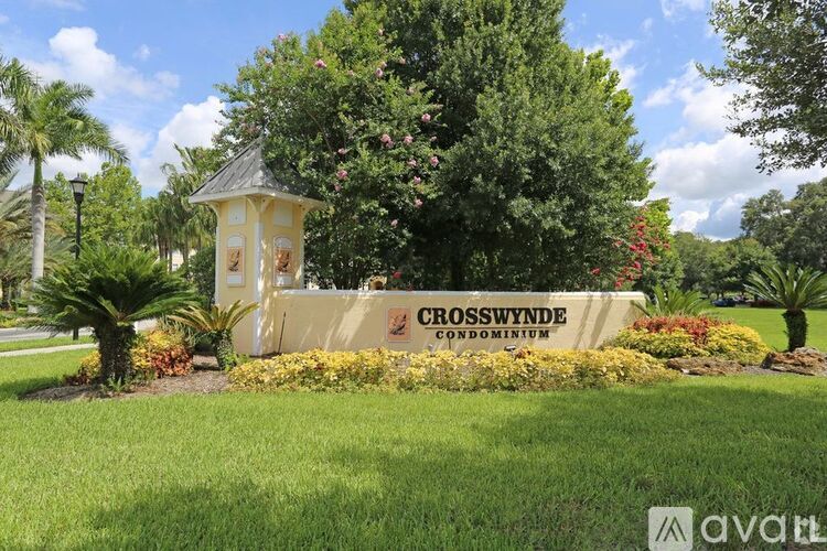 A sign for Crosswynde Condominium is surrounded by flowers and trees.