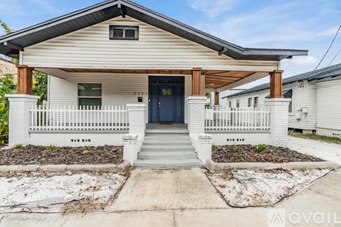 A house with a white fence and a dark blue door.