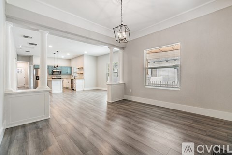 A spacious room with wooden flooring and a hanging light fixture.