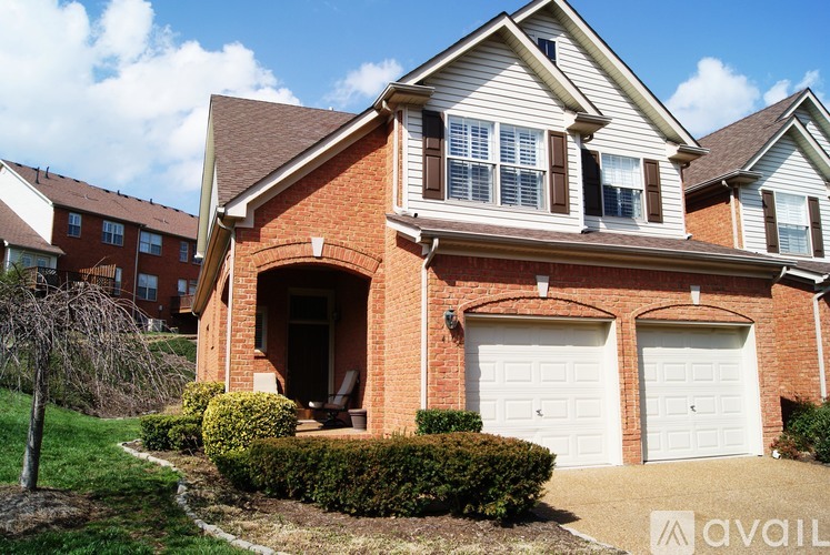 A house with a brown brick exterior and a white garage door.