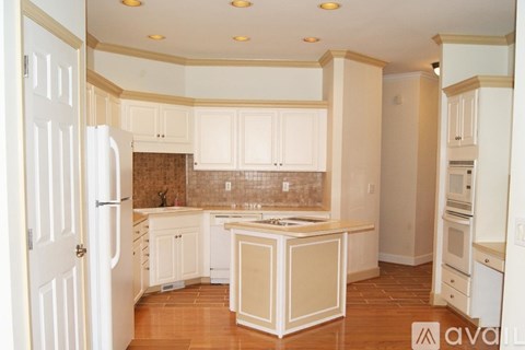 A kitchen with white cabinets and a wooden island.