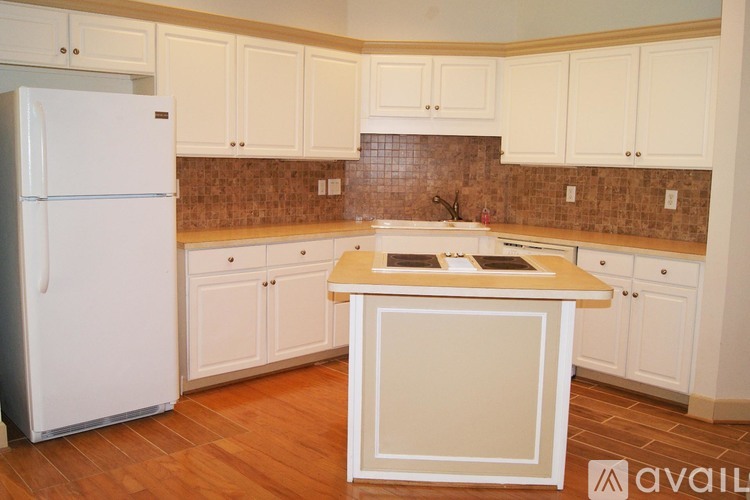 A kitchen with white cabinets and a white refrigerator.