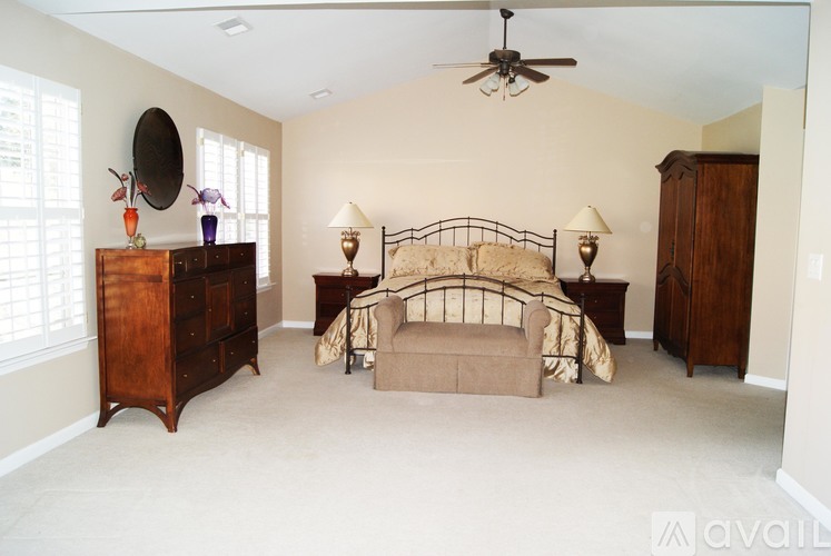 A bedroom with a bed, dresser, and ceiling fan.