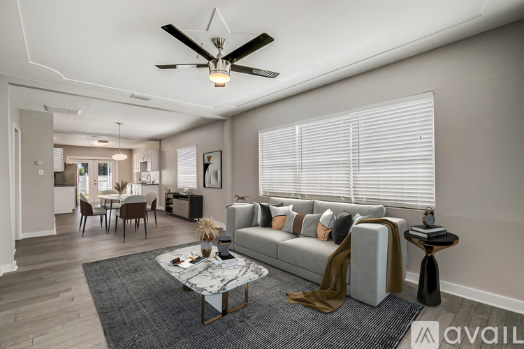 A living room with a grey couch, a coffee table, and a ceiling fan.
