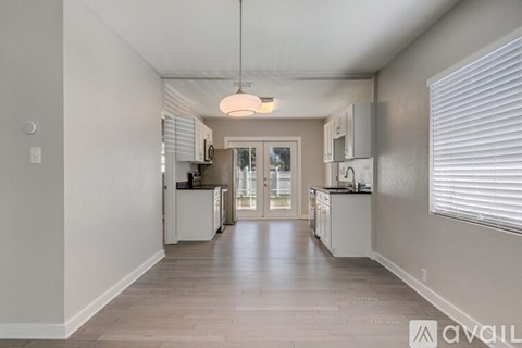 A kitchen with white cabinets and a wooden floor.